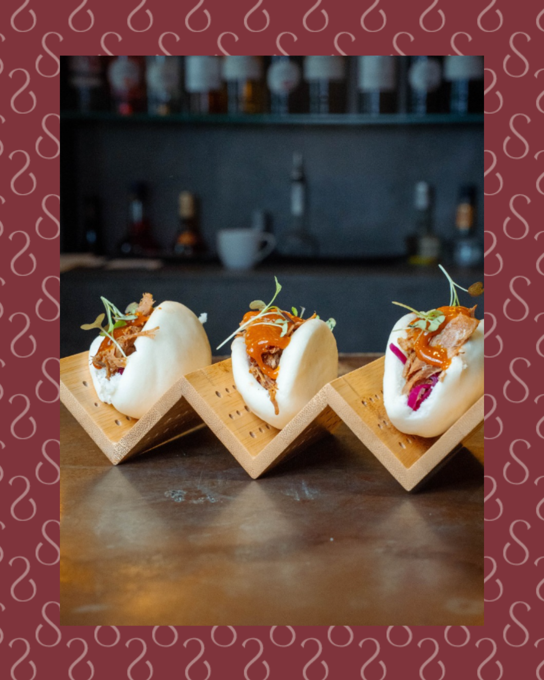 Trois bao buns garnis de viande effilochée et sauce épicée, tapas du bar Potus sur présentoirs en bois