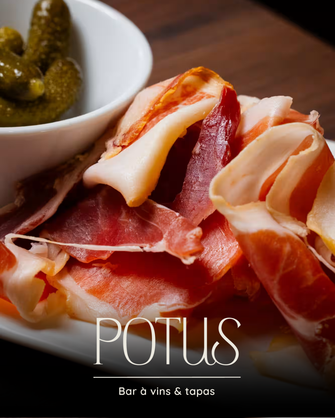 Assiette de charcuterie ibérique et cornichons du bar à vins Potus, avec logo et signature "Bar à vins & tapas"