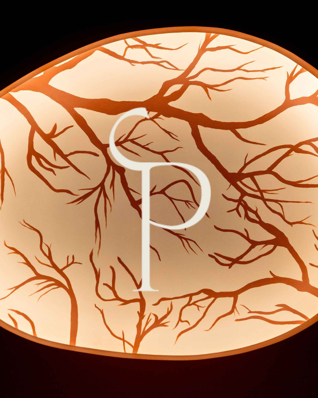 Monogramme doré du bar à vins Potus incrusté sur un abat-jour orange à motif de branches
