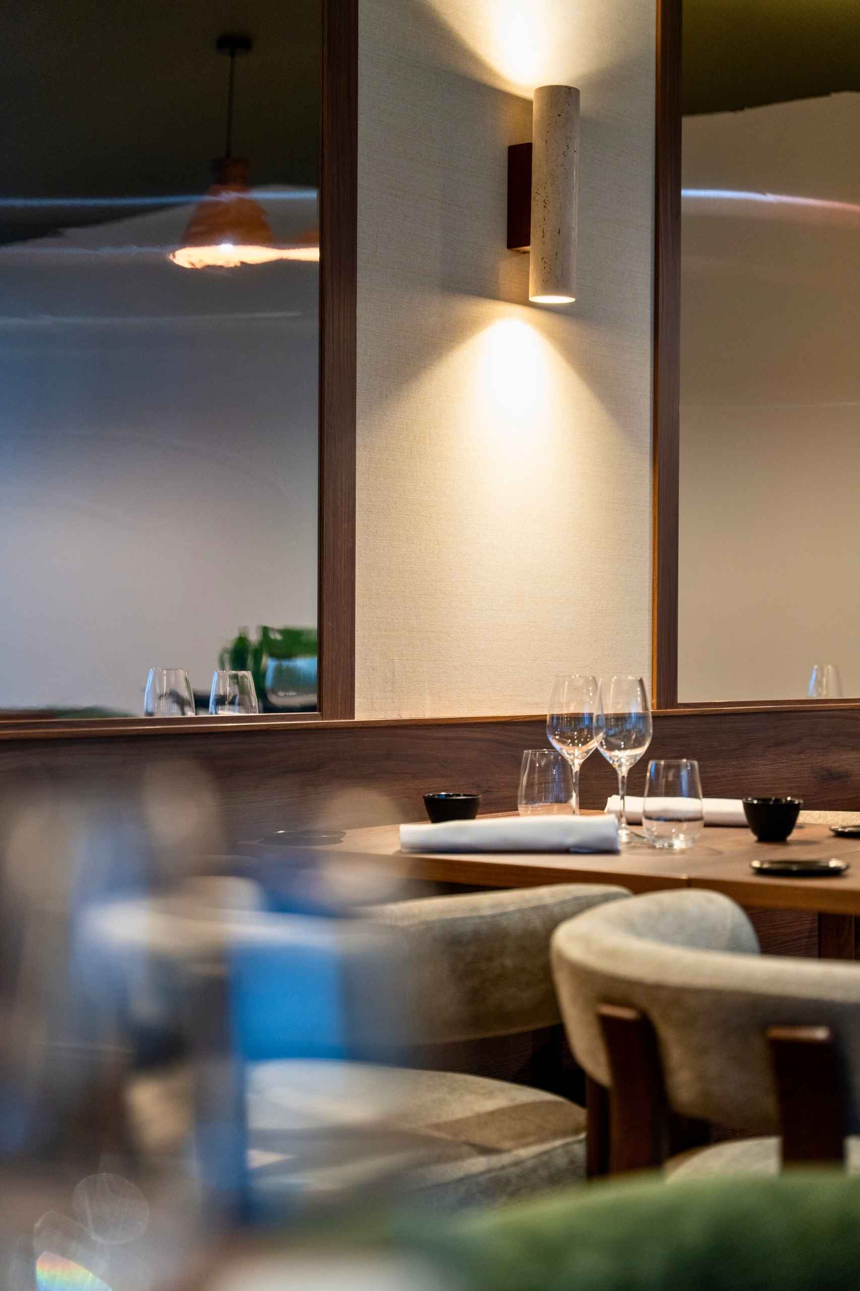 Détail table restaurant Mensa Tours avec miroir mural, applique et ambiance lumineuse – design intérieur restaurant