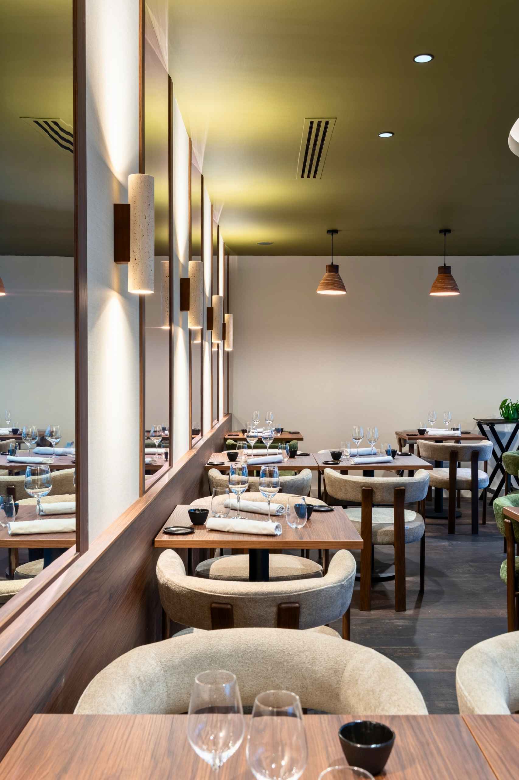 Ambiance intérieure du restaurant Mensa à Tours. Dialogue entre éclairage chaud, bois sombre et textiles pour une atmosphère maîtrisée.