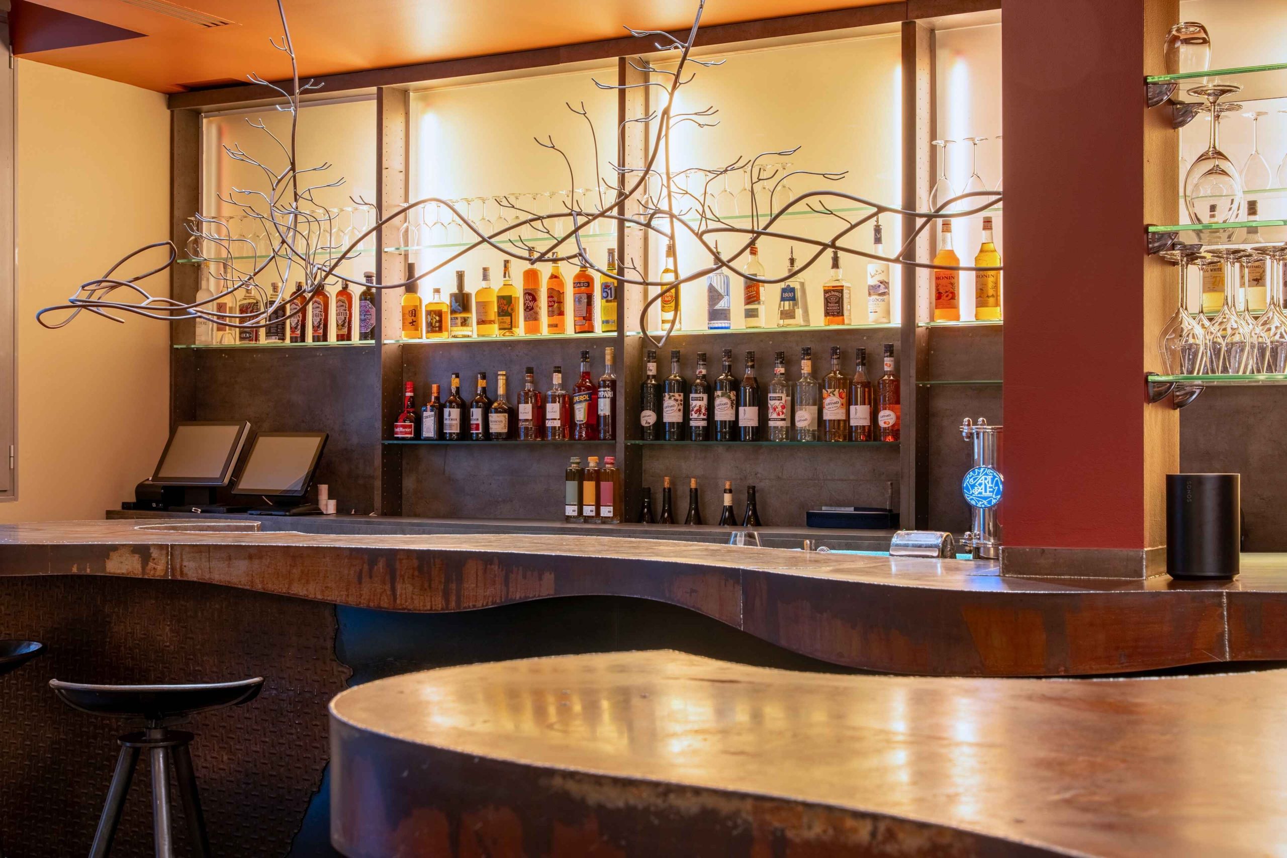 Bar à vins Potus à Tours avec comptoir sur mesure et sculpture métallique ramifiée au-dessus des bouteilles