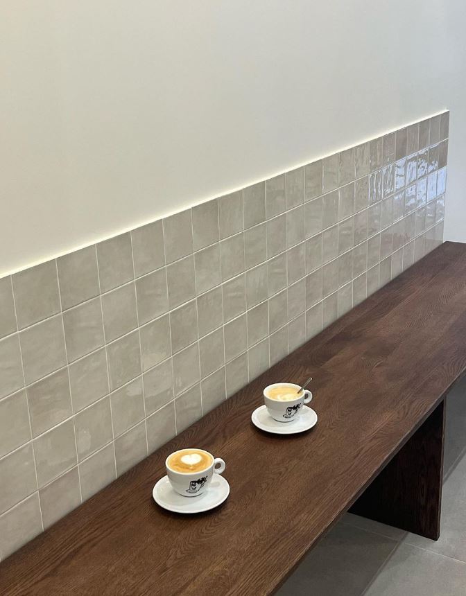 Banc intégré en bois avec crédence zellige dans coffee shop minimaliste
