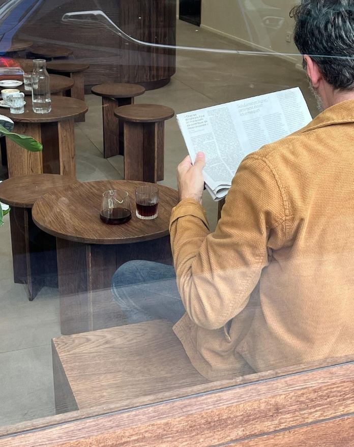 Client lisant assis à une table basse dans coffee shop minimaliste