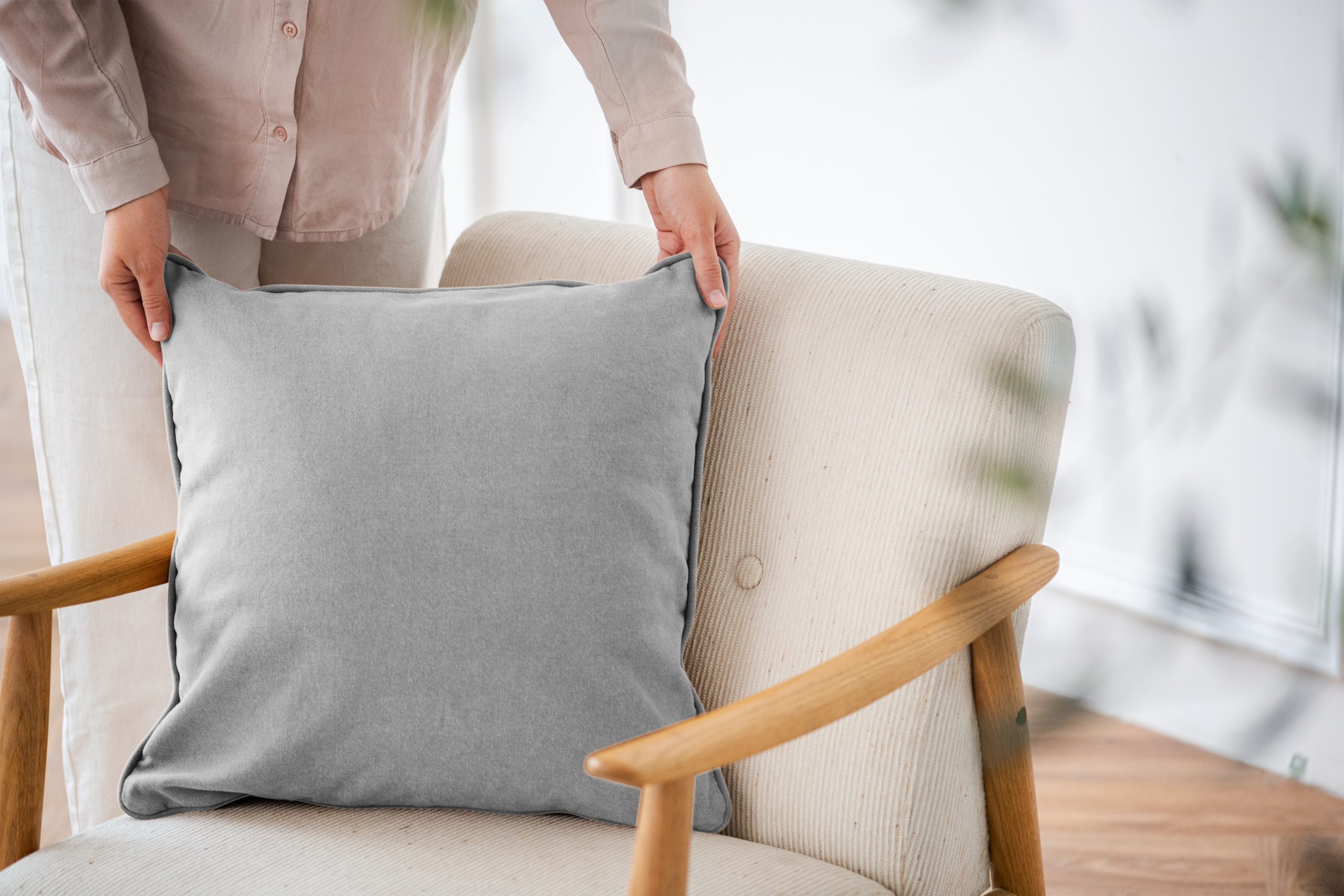 Décoratrice ajustant un coussin sur un fauteuil pour harmoniser l’ambiance