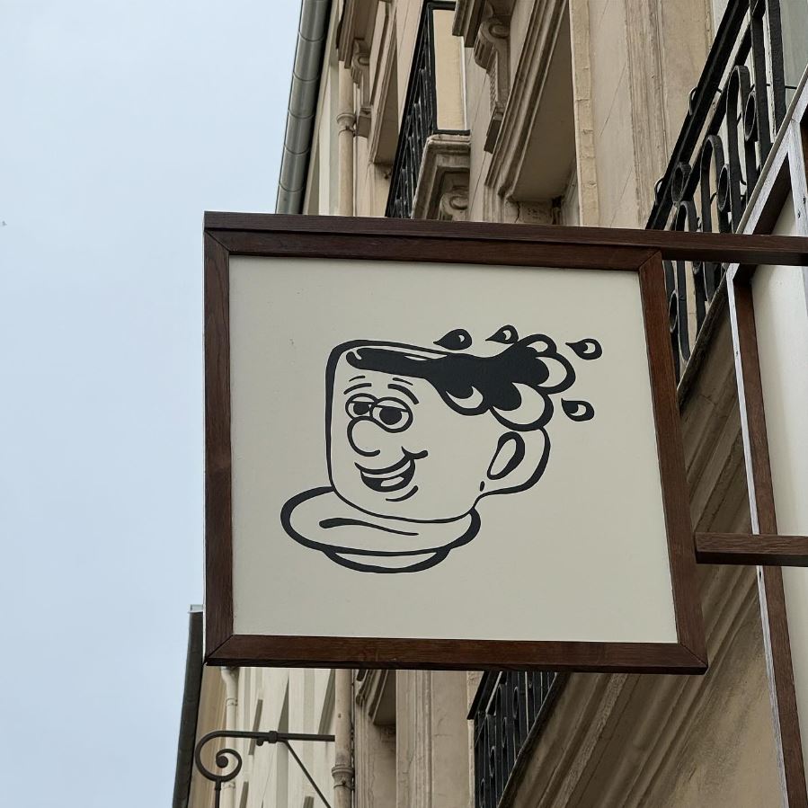 Enseigne suspendue avec logo du coffee shop en façade parisienne