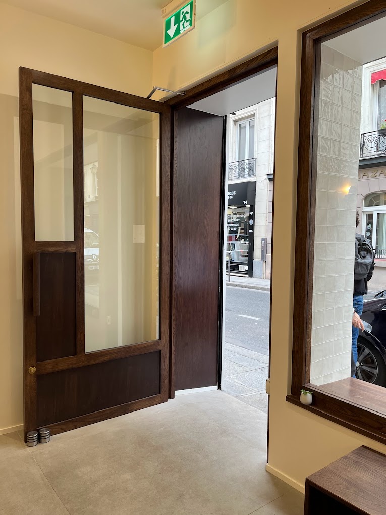 Entrée du coffee shop avec porte vitrée et menuiserie bois foncé