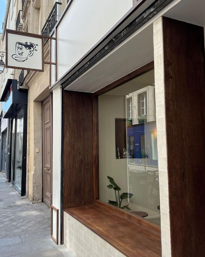 Façade du coffee shop avec vitrine en retrait et banc extérieur intégré en bois