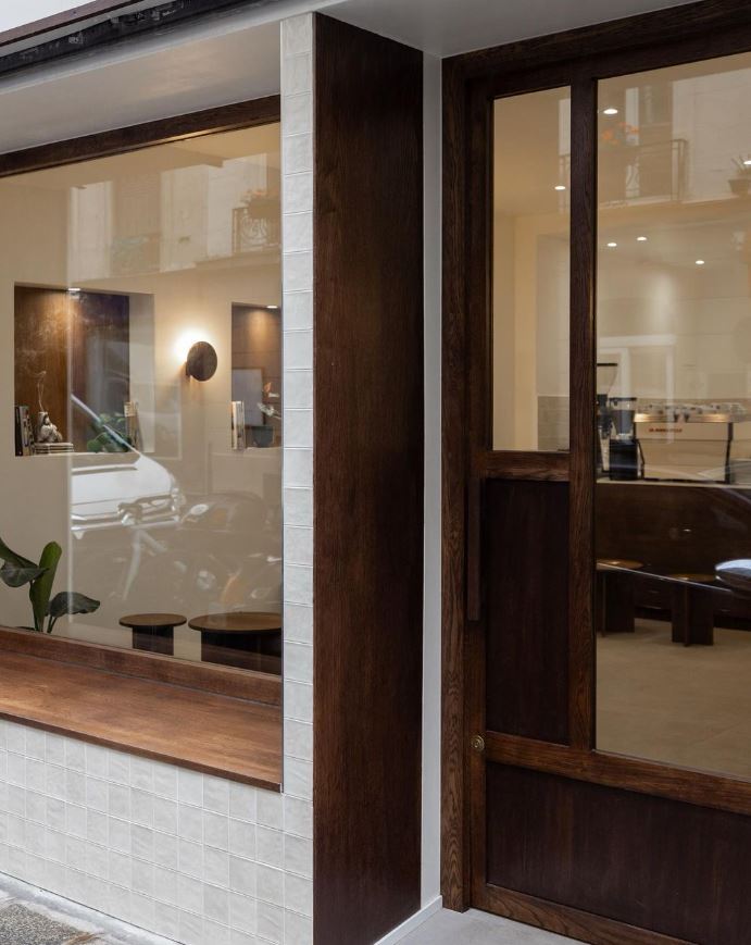 Façade du coffee shop avec zellige clair et menuiserie bois foncé à Paris