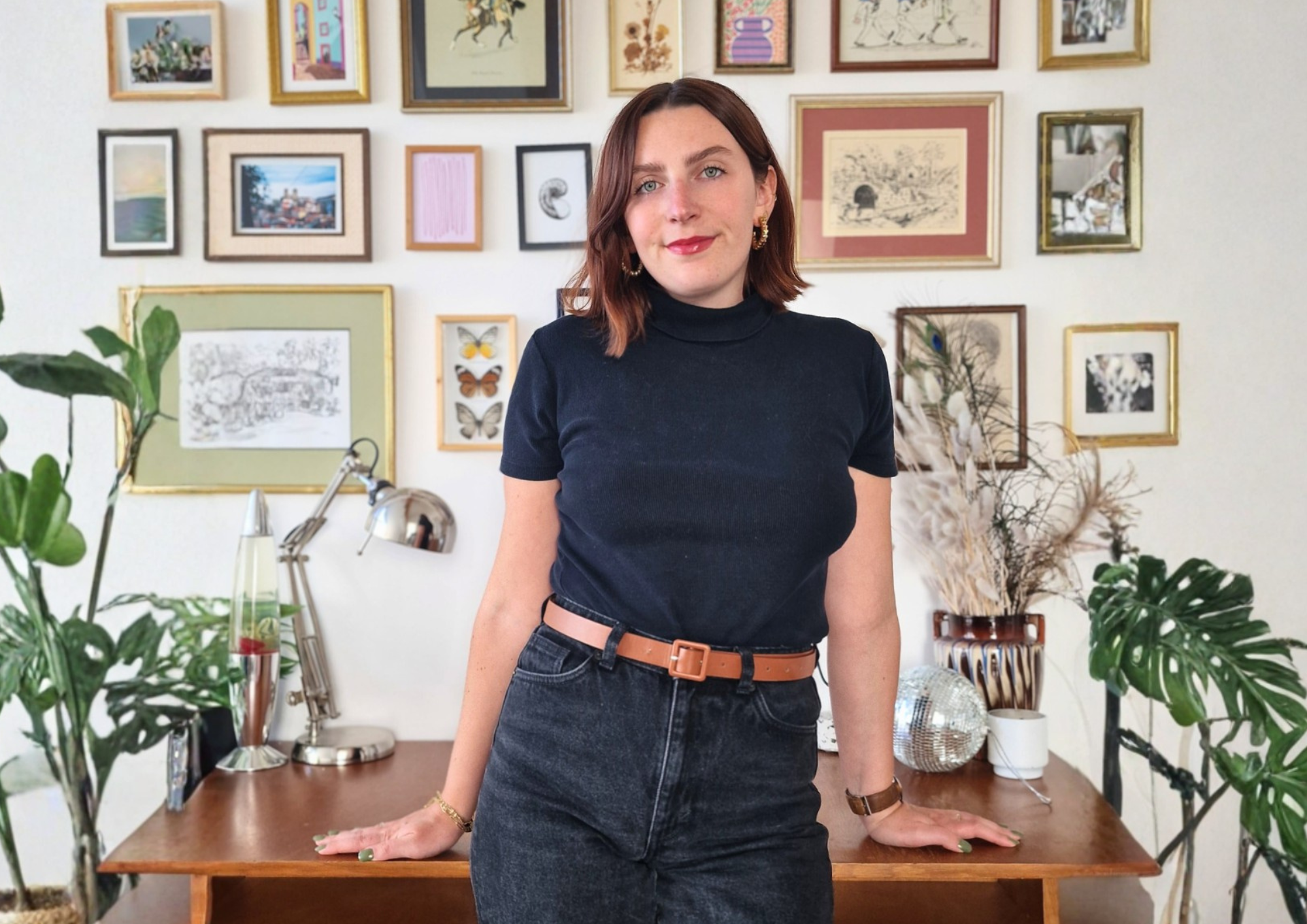Portrait de Marie Heuman, architecte d’intérieur, dans son studio avec mur de cadres décoratifs