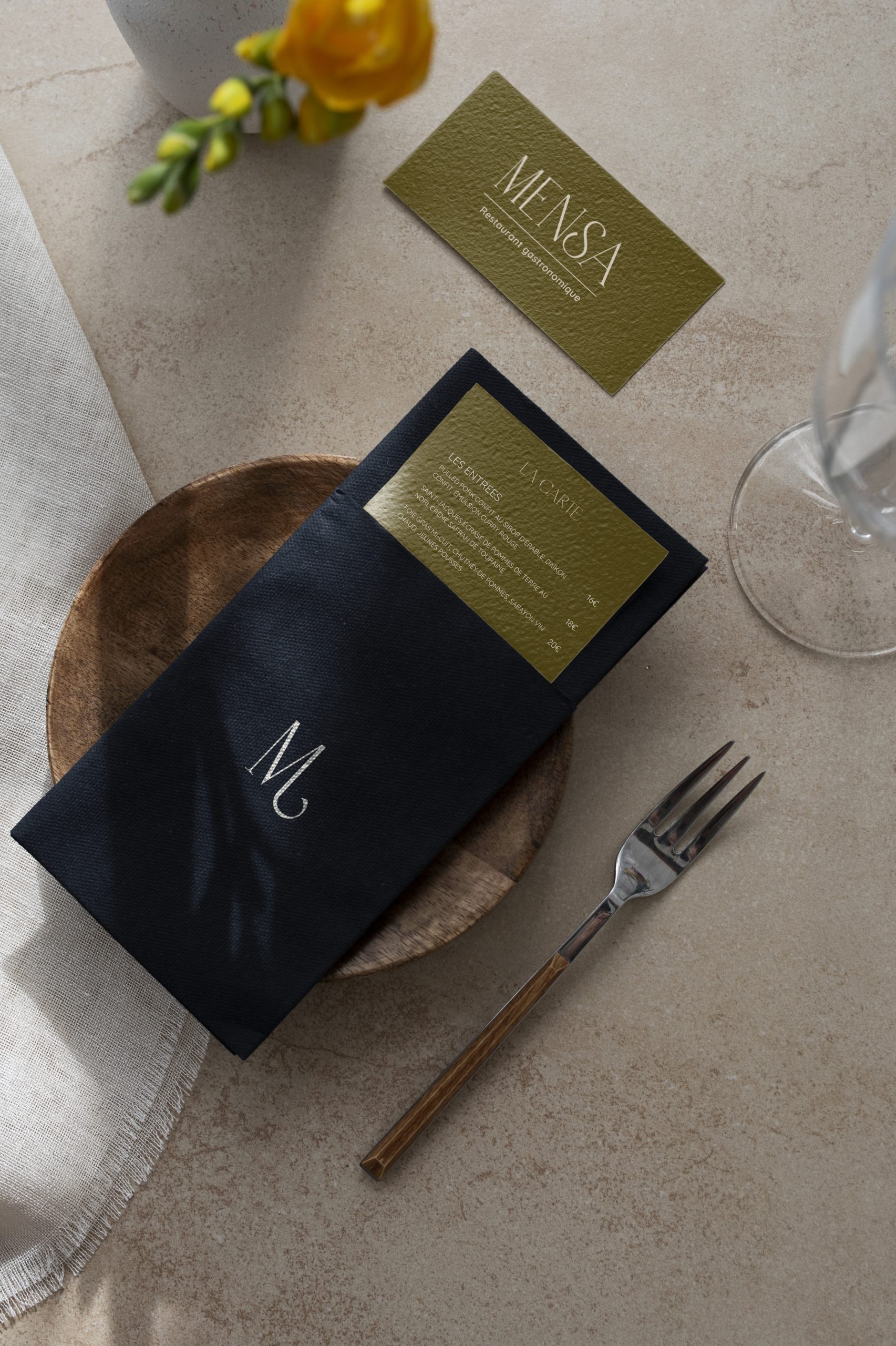 Carte du restaurant gastronomique MENSA glissée dans une serviette noire avec monogramme