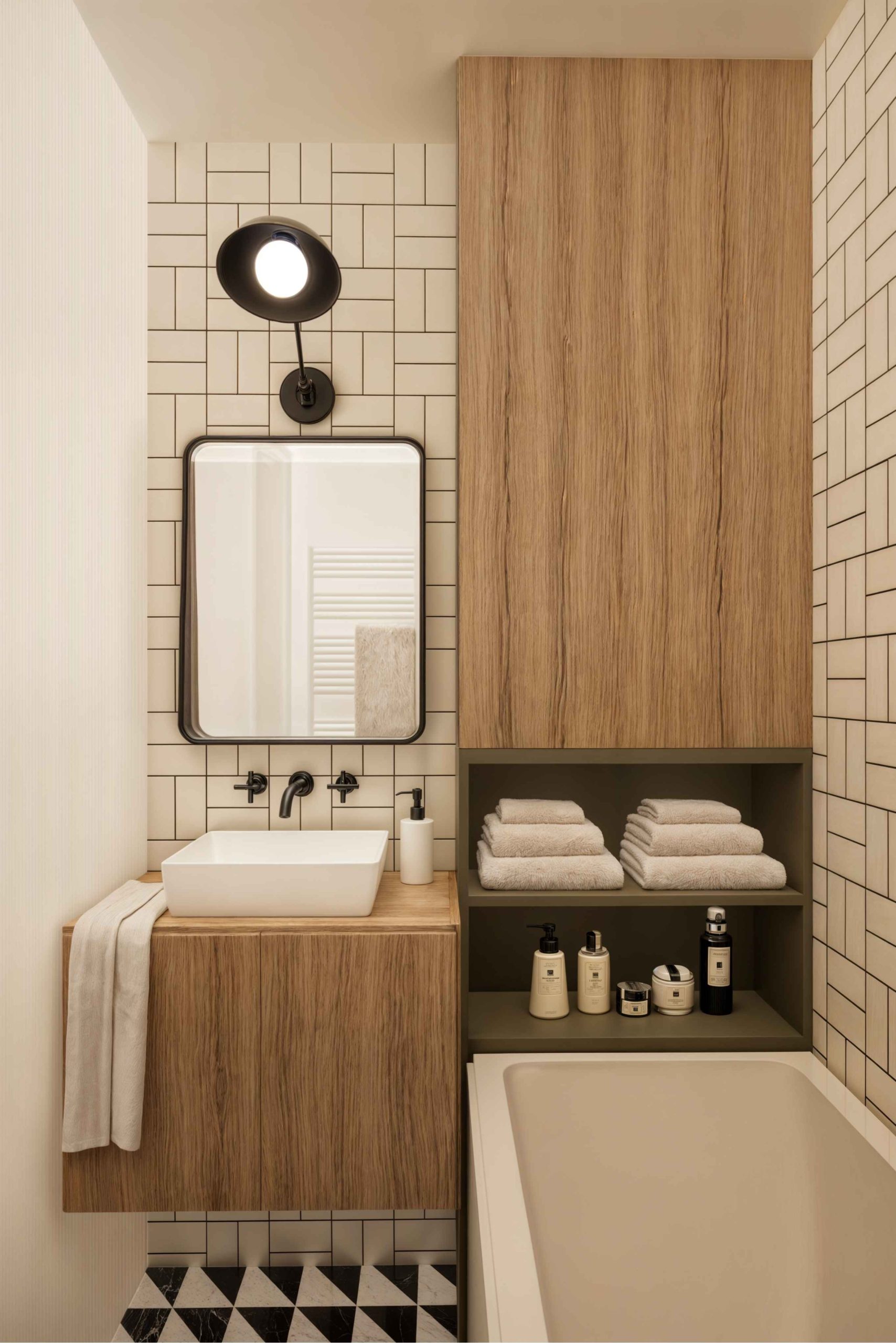 Salle de bains avec baignoire, meuble vasque en bois et carrelage graphique dans un appartement parisien rénové