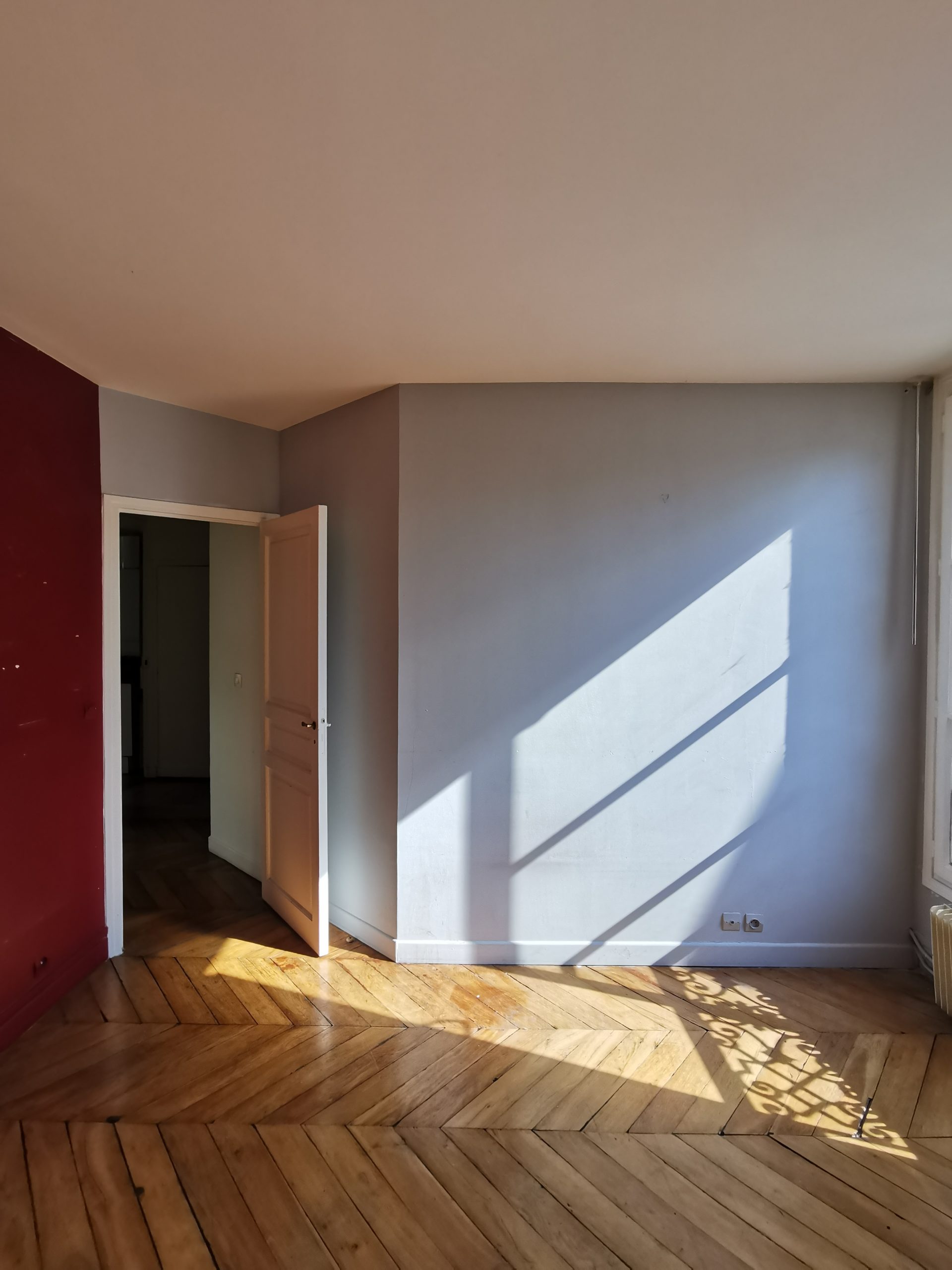 Pièce avant rénovation avec parquet point de Hongrie dans un appartement parisien