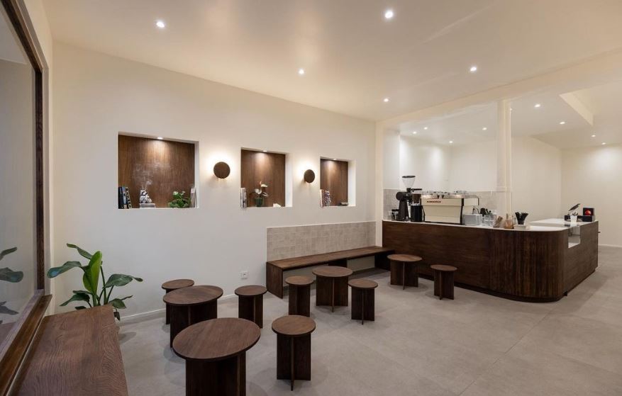 Salle du coffee shop avec mobilier en bois foncé et murs clairs
