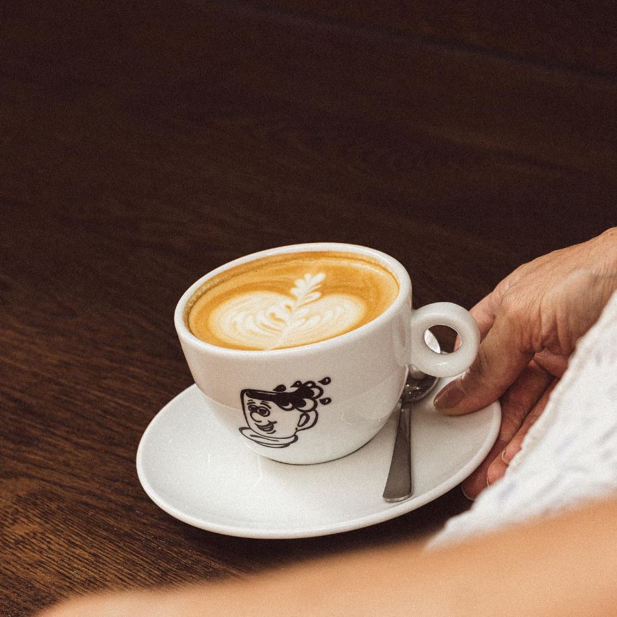 Cappuccino servi dans une tasse avec logo du coffee shop
