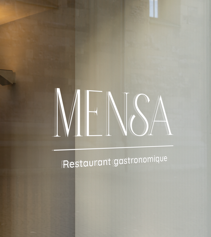 Logo MENSA appliqué sur la vitrine du restaurant gastronomique