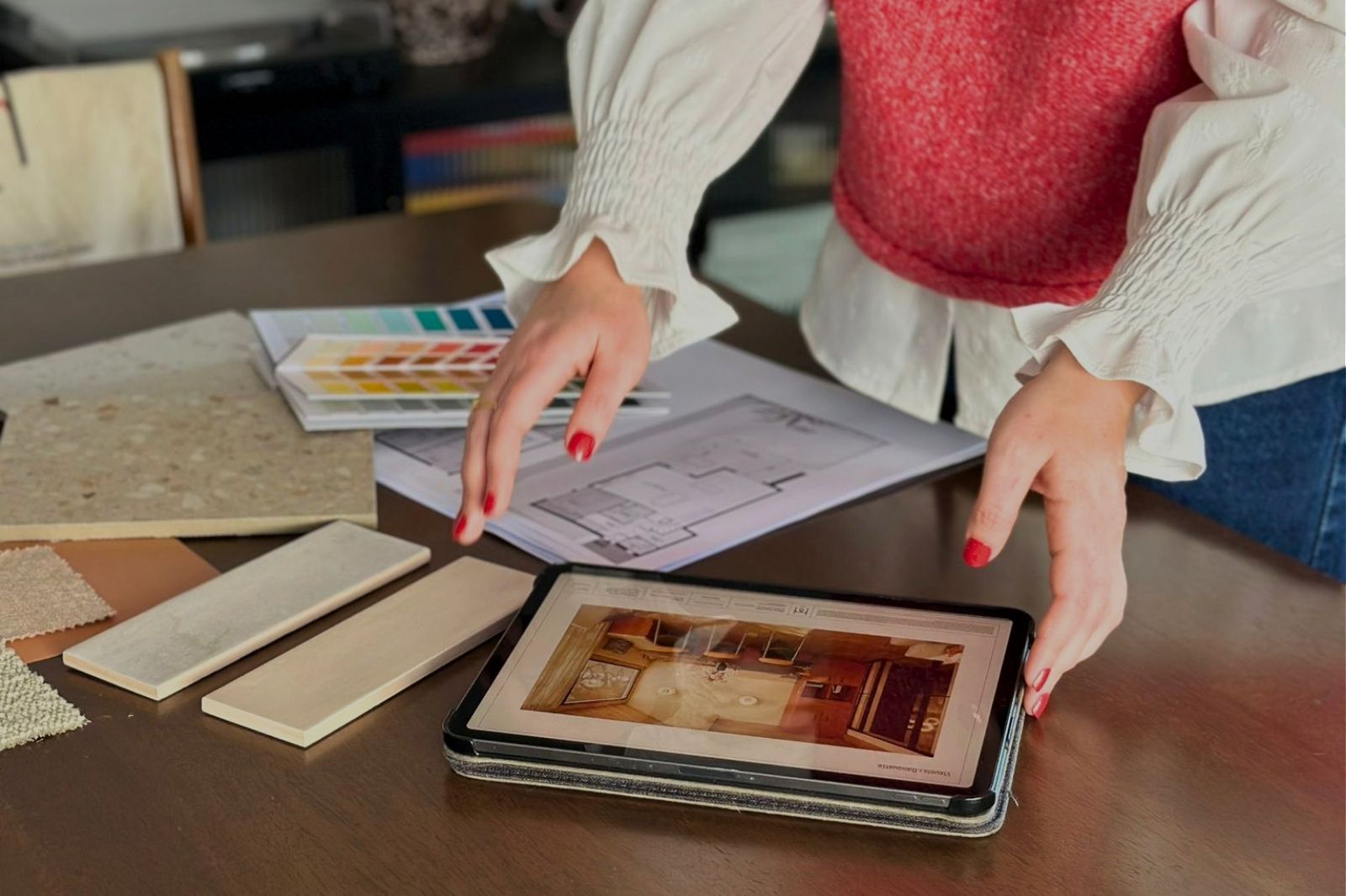 Architecte d’intérieur sélectionnant des matériaux et couleurs pour un projet d’aménagement intérieur avec plan et tablette