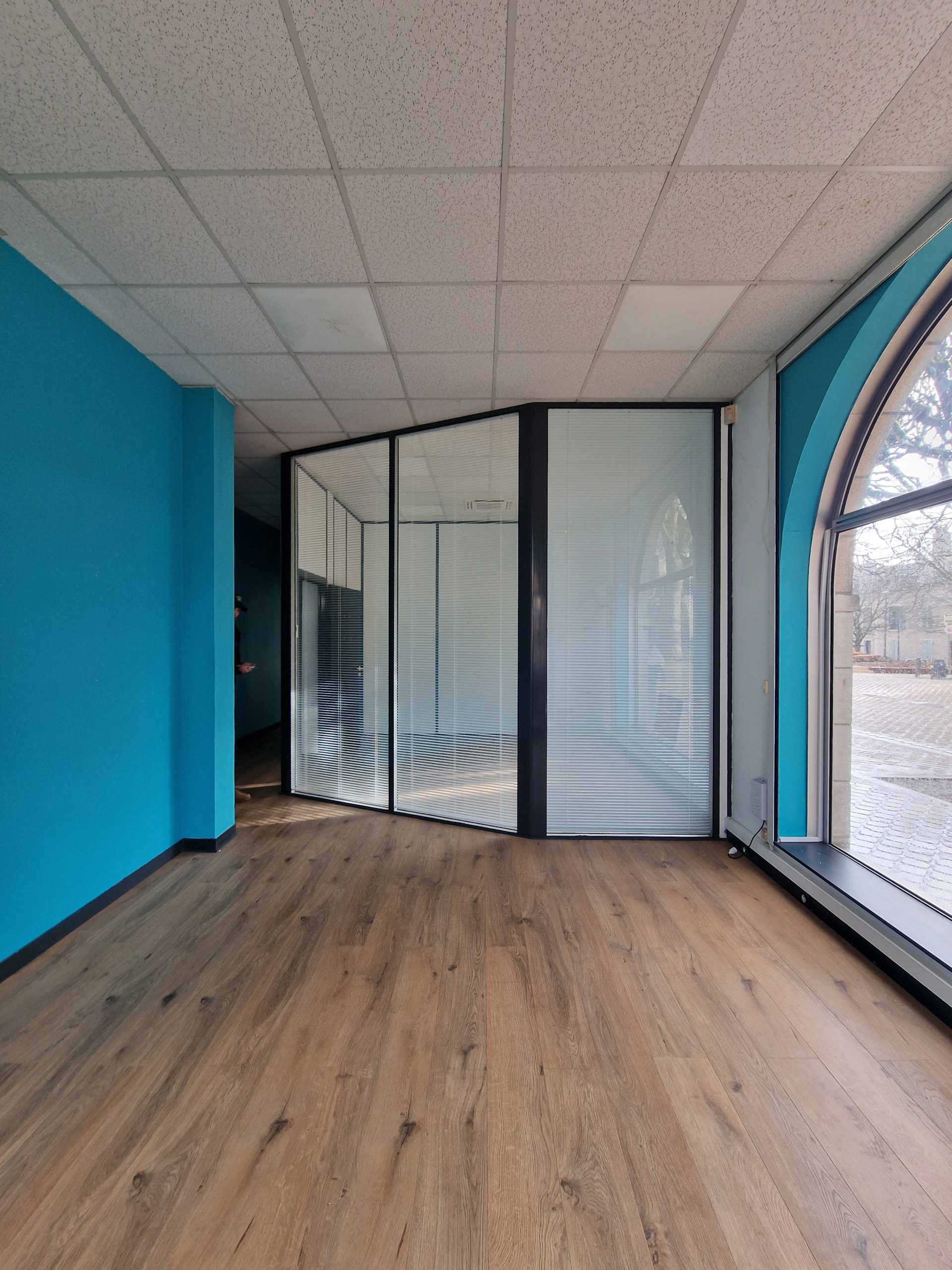 Ancien espace de bureaux avec cloisons vitrées à stores et murs turquoise, avant transformation en restaurant Table à Blois