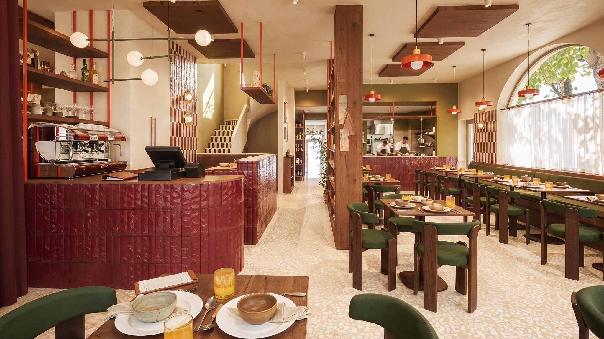 Vue d'ensemble du restaurant Table à Blois avec comptoir en zellige rouge, escalier à damier et cuisine ouverte sur la salle