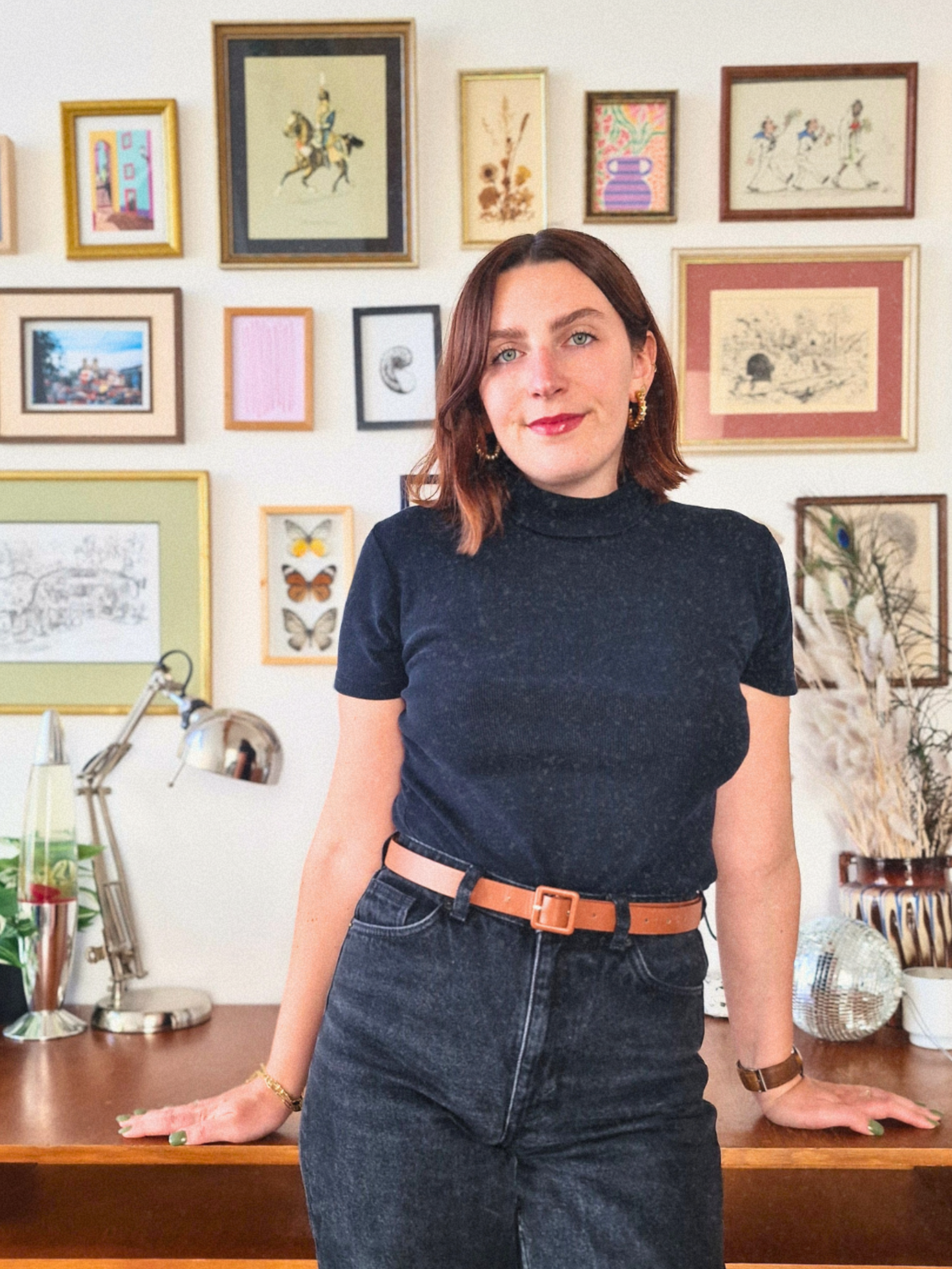 Portrait de Marie Heuman, architecte d’intérieur, dans son studio avec mur de cadres décoratifs